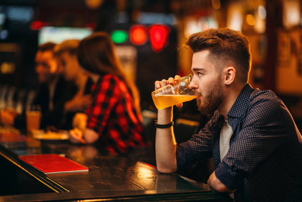 giovane che beve un bicchiere di birra al bancone del bar nel pub sportivo, felice svago dei tifosi di calcio
 - Foto, immagini