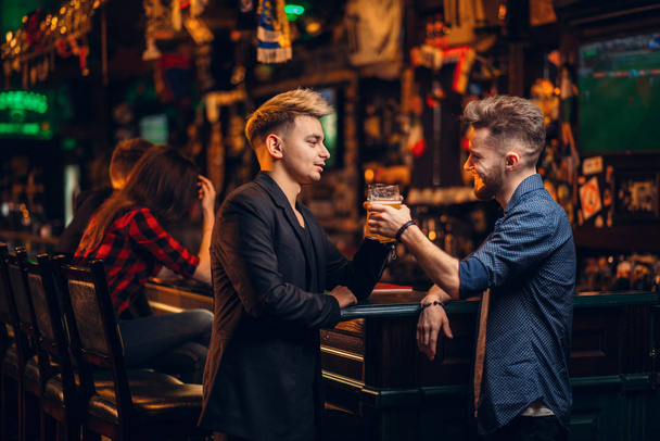 deux hommes au comptoir du bar levaient leurs verres avec de la bière au pub
 - Photo, image