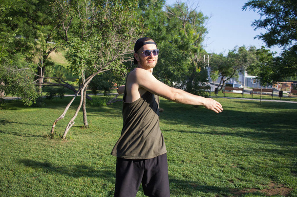 Nuori mies tekee harjoituksia ulkona puistossa
 - Valokuva, kuva