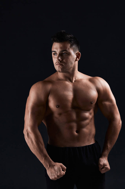 Muscular bodybuilder on black background.Strong athletic man sho - Foto, imagen