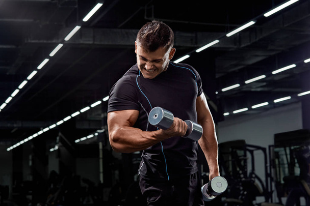 Muscular bodybuilder doing exercises with dumbbell in gym.Strong - Foto, Imagem