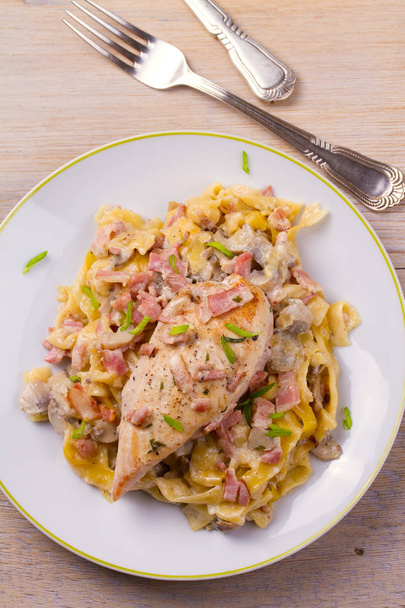 Chicken breast and egg noodles with bacon and mushrooms in creamy sauce. View from above, top, vertical  - Fotoğraf, Görsel
