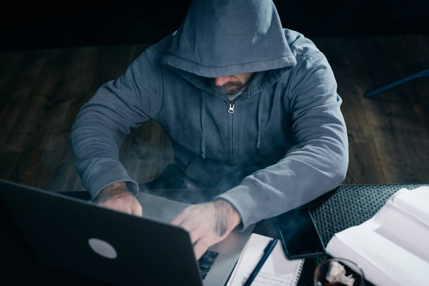 Um hacker de computador está digitando em um laptop em uma sala fumegante
.  - Foto, Imagem