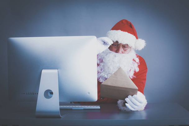 Santa Claus reading children letters and writing responses to them using laptop . - Foto, immagini