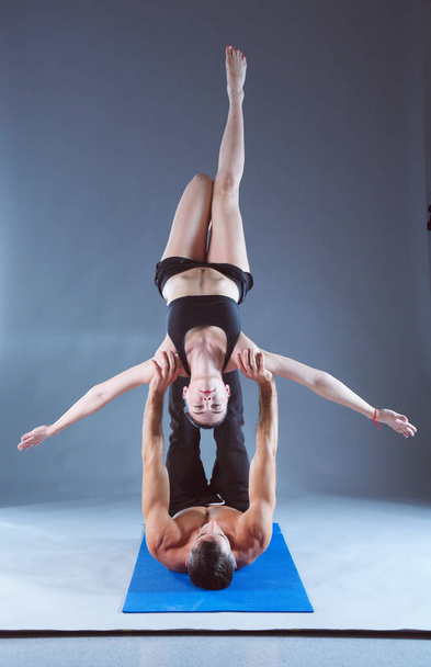 Young couple practicing acro yoga on mat in studio together. Acroyoga. Couple yoga. Partner yoga. - Photo, Image