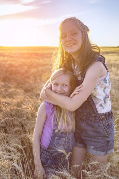 Beautiful sisters girl on the wheat field  - Foto, Imagen