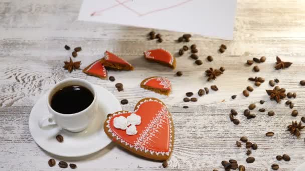 Люблю відносин. Концепція Святого Валентина. Вид зверху чашку кави і імбир печиво формі серця знаходяться на дерев'яні фону з кавових зерен навколо. Жіночий рукою ставить любов повідомлення Примітка, 4 к - Кадри, відео
