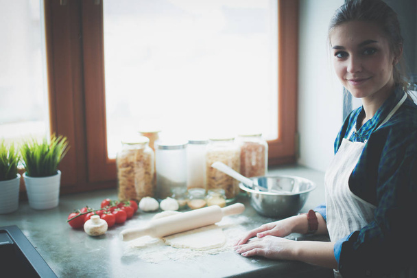 Beautiful woman cooking cake in kitchen standing near desk. - Fotó, kép