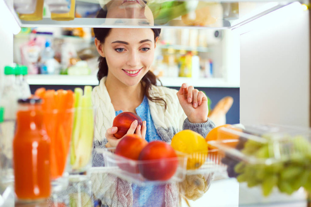 Portrait of female standing near open fridge full of healthy food, vegetables and fruits. Portrait of female - Foto, Imagen