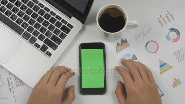 Businessman using smartphone with green screen at white office table background. Top view. Male hands scrolling pages, zooming, tapping on touch screen. Office desk background - Footage, Video