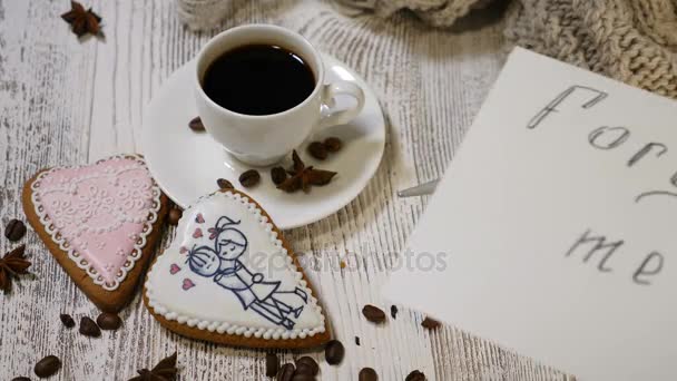 Prosit o odpuštění. Láska vztahy. Horní pohled na šálek kávy a zázvor sušenky ve tvaru na dřevěné pozadí s kávová zrna kolem srdce. ruka klade odpusť mi zprávy Poznámka - Záběry, video