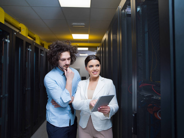 engineer showing working data center server room to female chief - Fotó, kép