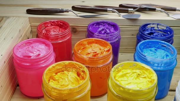 colorful of Plastisol Ink in the clear glass can on the wooden box for screen print tee shirt. Plastisol ink useful in tee shirt factory and in industry for export - Footage, Video