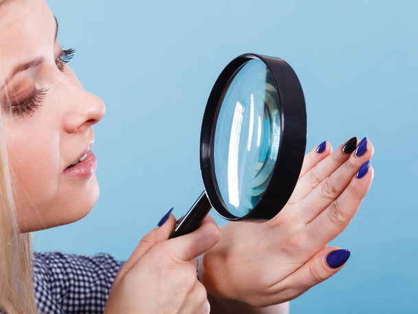 Woman looking at nails through magnifying glass - Фото, зображення