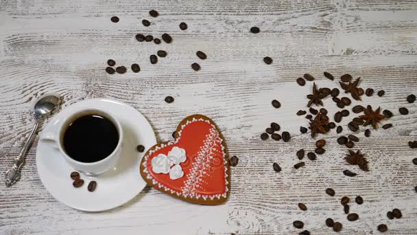 Love relations. St. Valentine concept. Top view of cup of coffee and a ginger biscuit heart shaped are on wooden background with coffee beans around. hand puts I Need You message note, 4 k - Footage, Video
