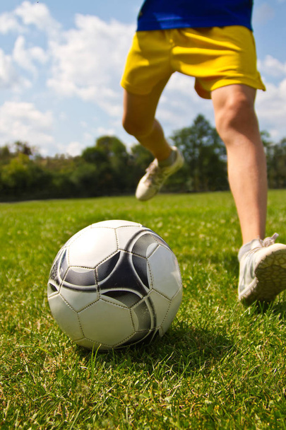 Legs of soccer player kicking the ball - Fotó, kép