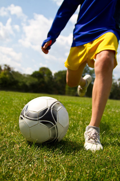 Piernas del jugador de fútbol pateando la pelota
 - Foto, Imagen