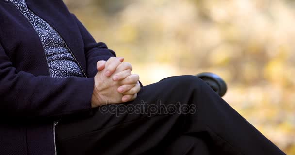 Huolestunut vanhempi nainen hankaa kätensä penkillä puistossa lähikuva
. - Materiaali, video