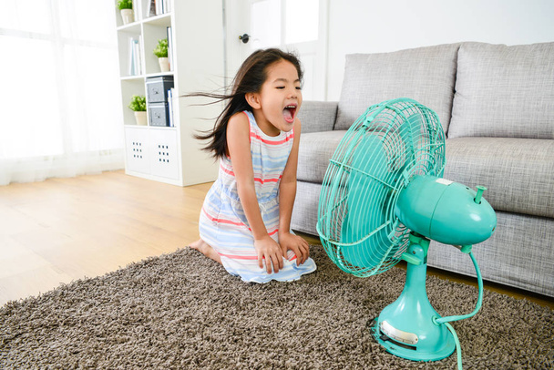 Gelukkig klein meisje elektrische ventilator thuis spelen - Foto, afbeelding