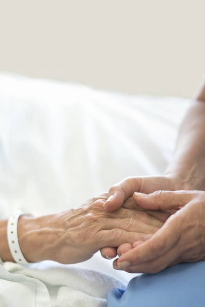Infirmière tenant la main du patient masculin dans le lit d'hôpital
. - Photo, image