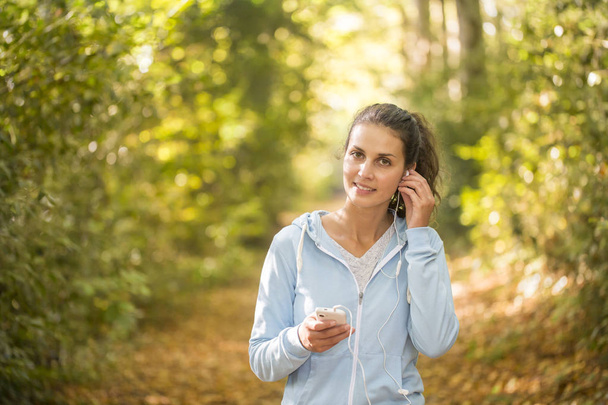 woman using smartphone after running on forest in autumn - Foto, Imagen