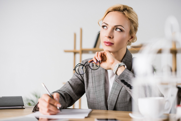 portrait of pensive businesswoman looking away at workplace - Fotoğraf, Görsel