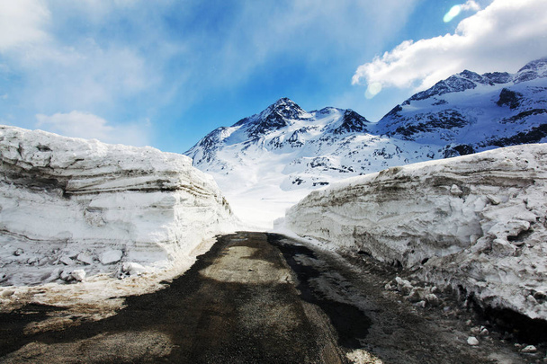 Vista incrível da paisagem coberta de neve e uma estrada e uma montanha nos alpes suíços
 - Foto, Imagem