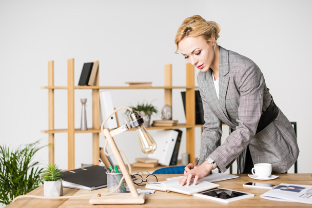 portrait of businesswoman making notes in notebook at workplace - Photo, Image