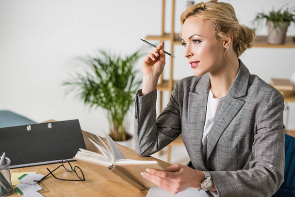 side view of pensive businesswoman with notebook at workplace - Foto, Imagen