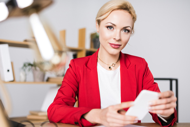 portrait of beautiful businesswoman with smartphone at workplace in office - Fotoğraf, Görsel