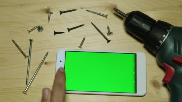 Ηλεκτρικό κατσαβίδι και smartphone με μια πράσινη οθόνη. - Πλάνα, βίντεο