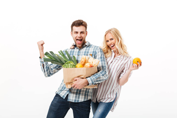Retrato de una alegre pareja sosteniendo bolsa de compras de papel
 - Foto, imagen