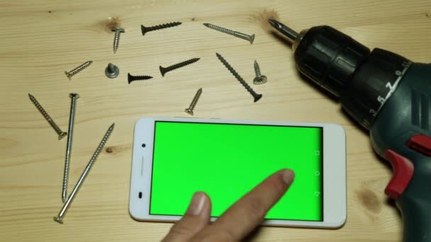 Electric screwdriver and smartphone with a green screen for your content. - Footage, Video