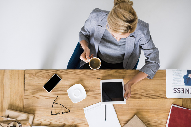Blick auf Geschäftsfrau mit Tasse Kaffee und Tablet am Arbeitsplatz im Büro - Foto, Bild