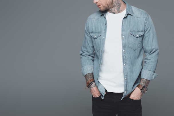 cropped shot of stylish young tattooed man standing with hands in pockets isolated on grey - Фото, зображення