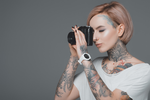 beautiful girl with tattoos photographing with camera isolated on grey - 写真・画像