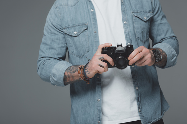 cropped shot of young man with tattoos holding camera isolated on grey - Foto, Imagen