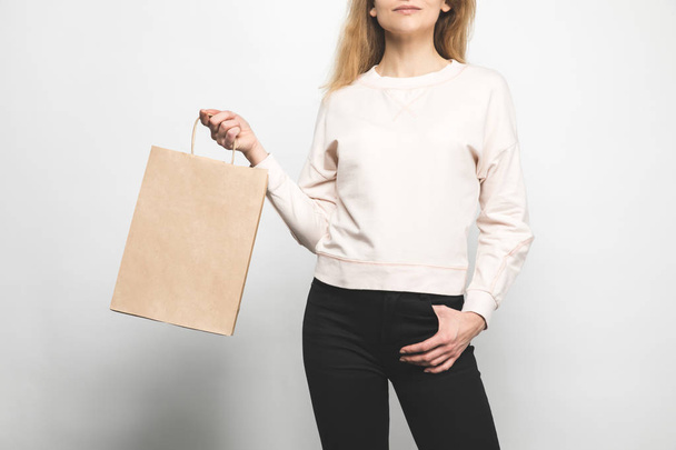 cropped shot of woman in blank sweatshirt on white with shopping bag - Foto, Bild