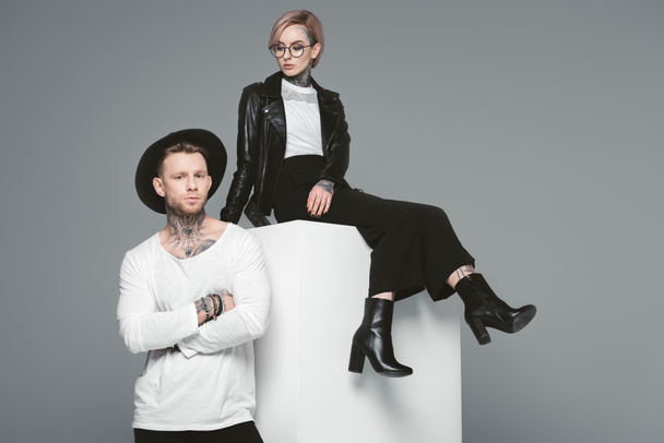 beautiful stylish young couple with tattoos posing together isolated on grey - 写真・画像