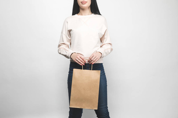 young woman in blank sweatshirt on white with shopping bag - Photo, Image