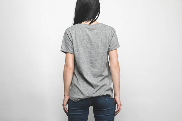 rear view of young woman in blank grey t-shirt on white - Фото, изображение
