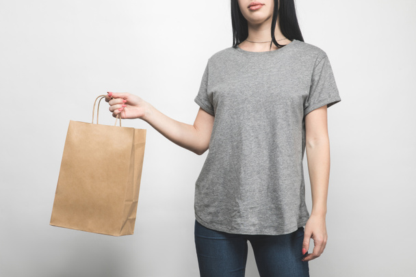 recortado tiro de mujer joven en blanco camiseta gris en blanco con bolsa de compras
 - Foto, imagen