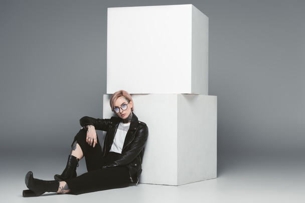 stylish tattooed girl sitting near white cubes, isolated on grey - Valokuva, kuva
