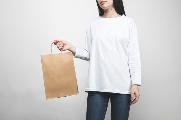 mujer joven en sudadera en blanco con bolsa de compras
 - Foto, Imagen