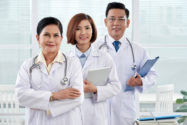 Aziatische artsen, werknemers van medische kliniek glimlachen en kijken naar camera - Foto, afbeelding