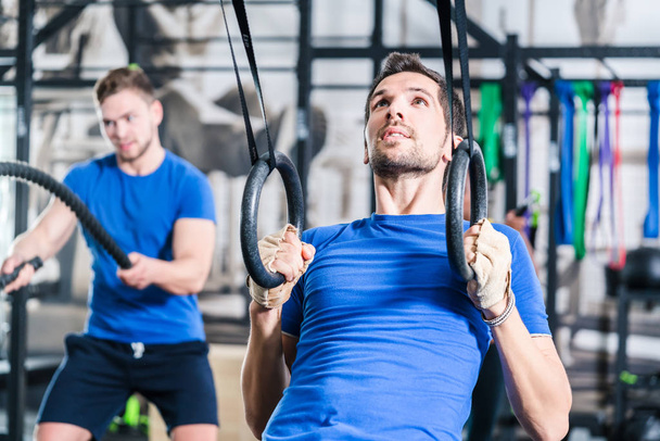 Man at rings doing fitness exercise in gym - Photo, Image