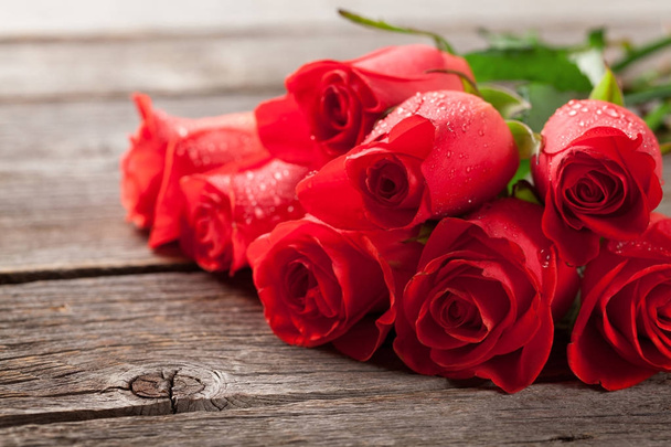 Tarjeta de felicitación de San Valentín con rosas rojas sobre mesa de madera
 - Foto, Imagen