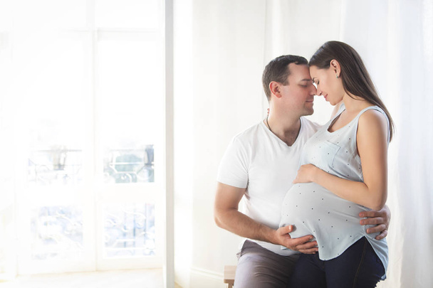 Pregnant woman and young man together indoors - Foto, immagini