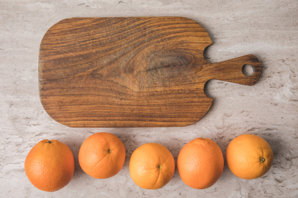 Widok z góry wiersza pomarańcze i deska do krojenia na marmurowym stoliku  - Zdjęcie, obraz