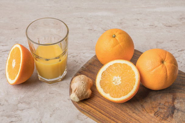 vista de ángulo alto de naranjas y jengibre en la tabla de cortar
  - Foto, imagen